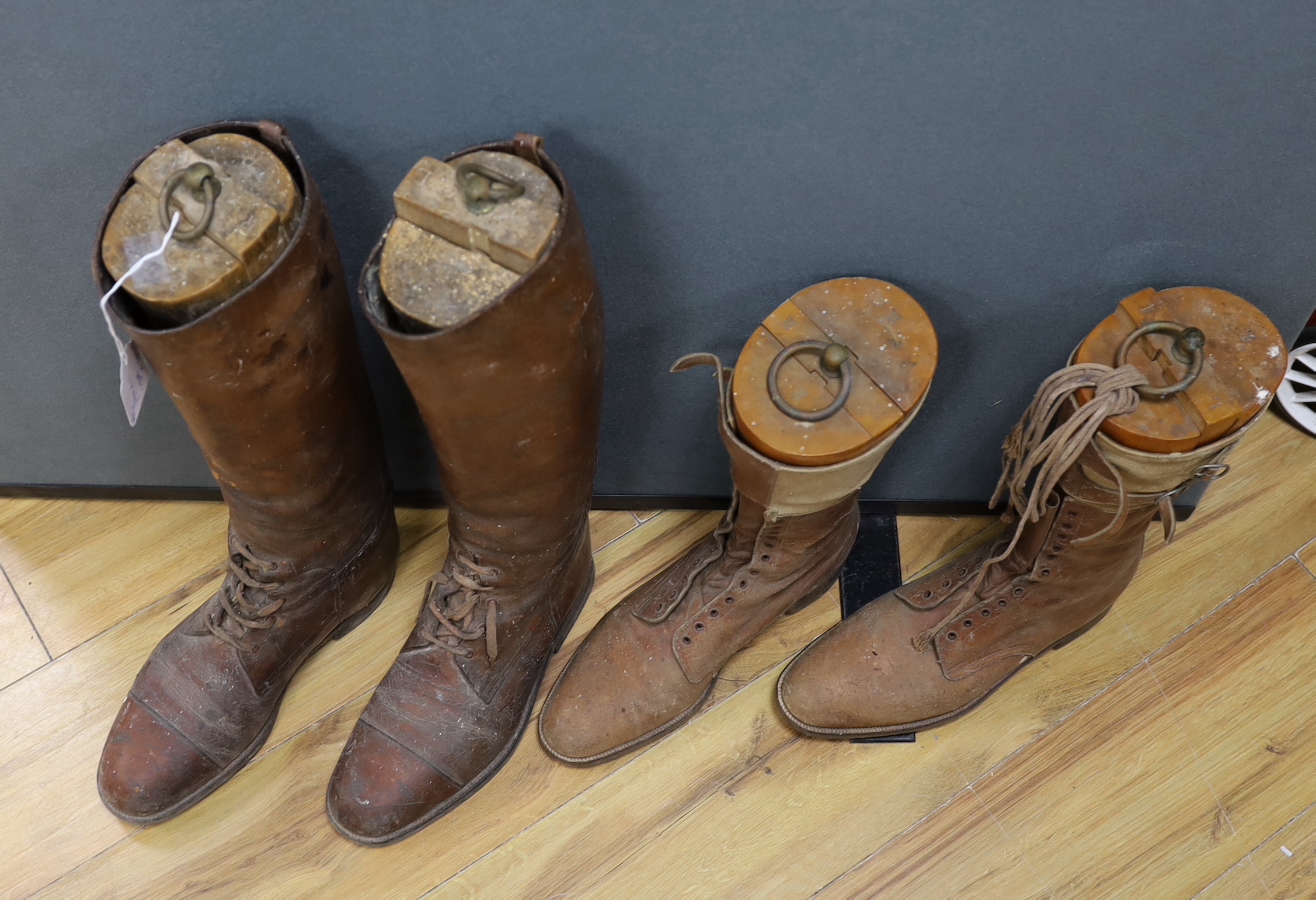 A pair of gentlemen’s brown leather laced riding boots together with a shorter pair of tan leather and canvas laced boots, both boots with wooden trees, tallest 51cm high